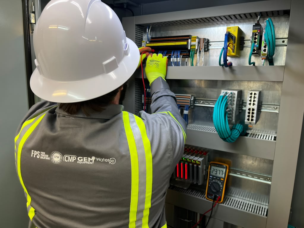 Mosaix Mechanical electrician testing a completed control panel with a multimeter before shipment