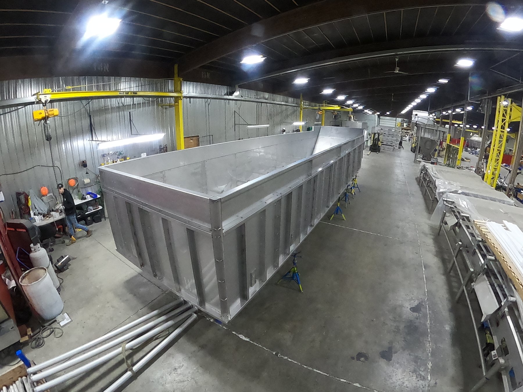 Long open-top stainless steel tank on support stands during fabrication at Mosaix Mechanical