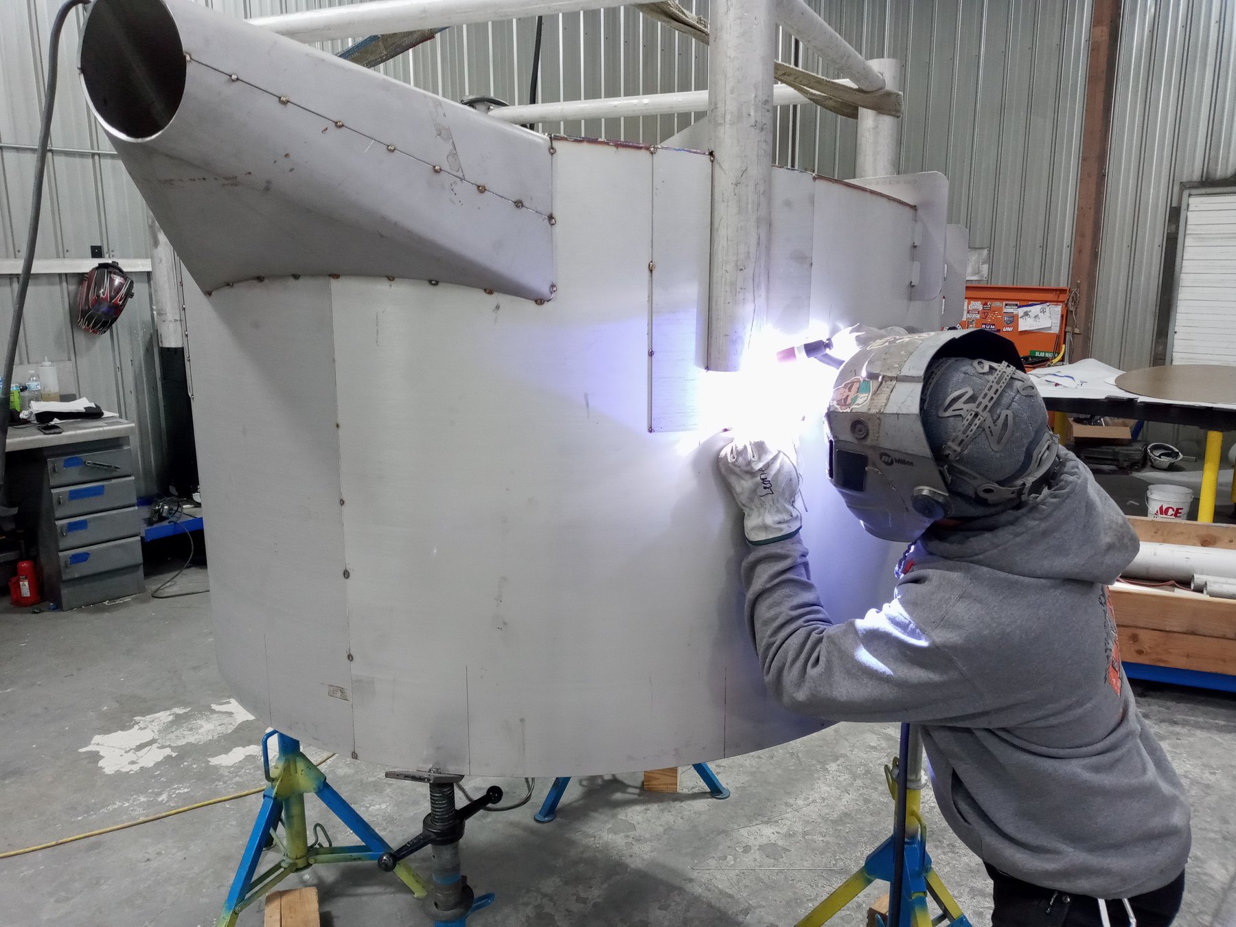 Mosaix Mechanical welder welding a large stainless steel hopper shell on jack stands in the Burley, Idaho fabrication shop